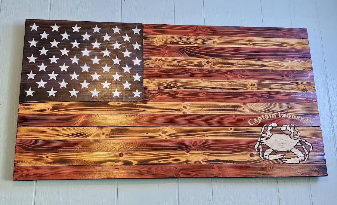Burned-wood American flag with Captain Leonard's crab logo on the dining room wall